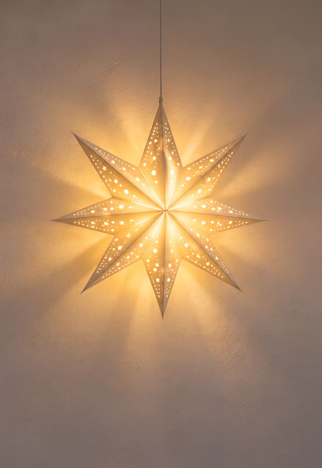 壁に灯るクリスマスの紙の星ランタン（iPhone Duo の外側の画面用壁紙、文字なし）